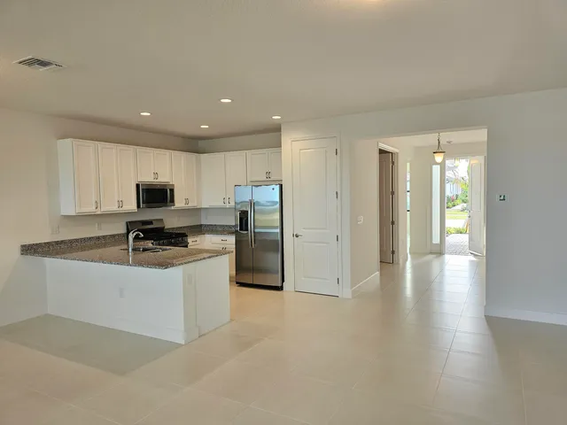 a kitchen with stainless steel appliances granite countertop a refrigerator a sink a stove and white cabinets