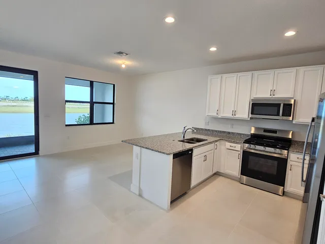 a kitchen with granite countertop white cabinets and stainless steel appliances