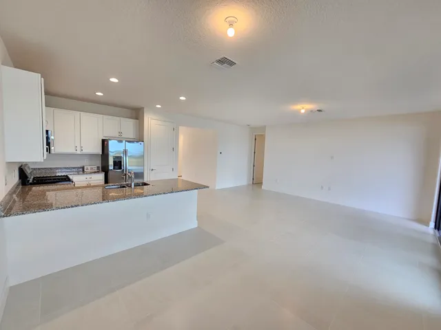 a large kitchen with stainless steel appliances a large counter top a stove a sink a refrigerator and white cabinets