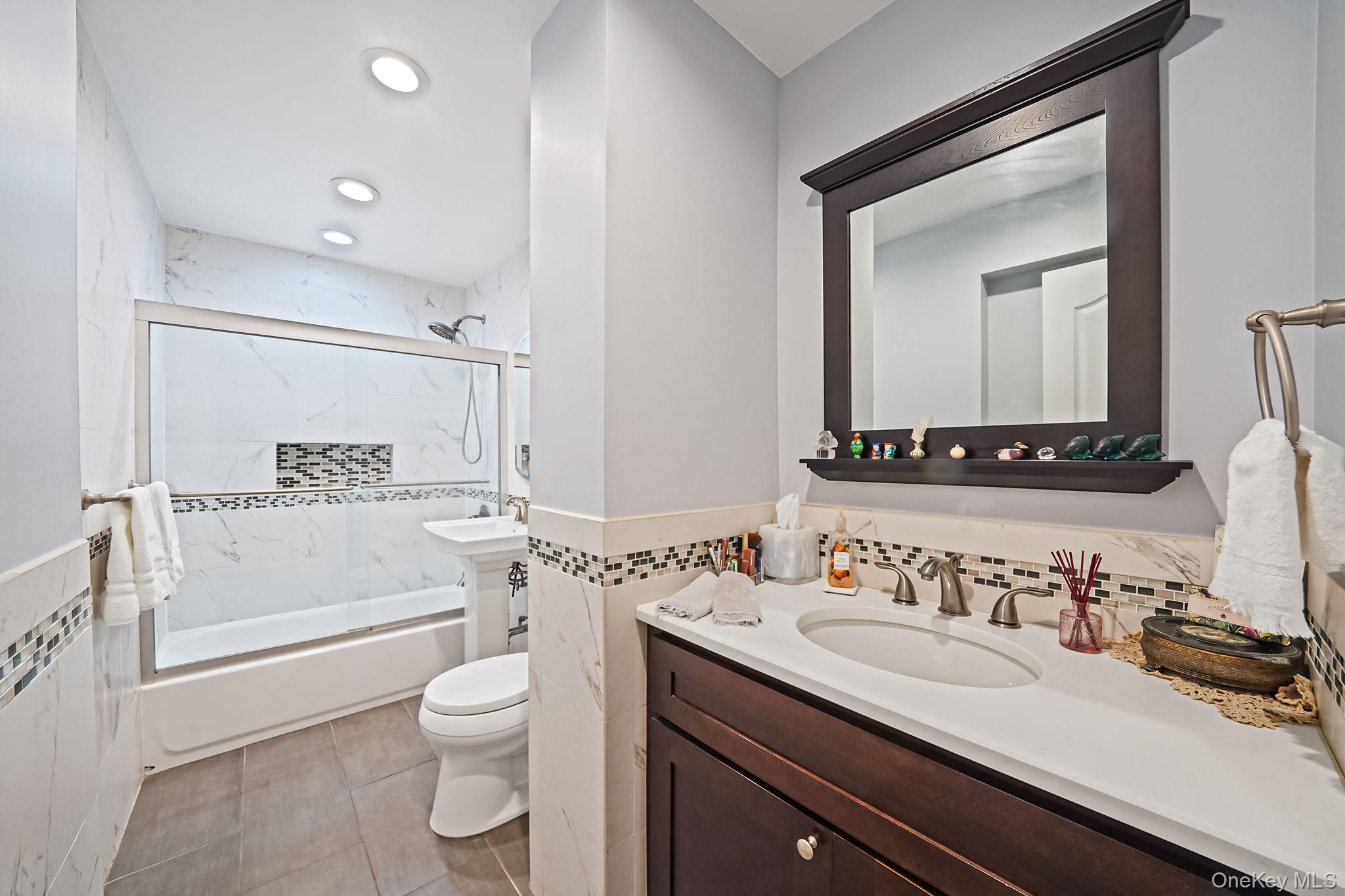 18-35 Corporal Kennedy Street, Unit 2B Queens, NY 11360 - Photo 9 of 25 a bathroom with a granite countertop sink a toilet and a bathtub