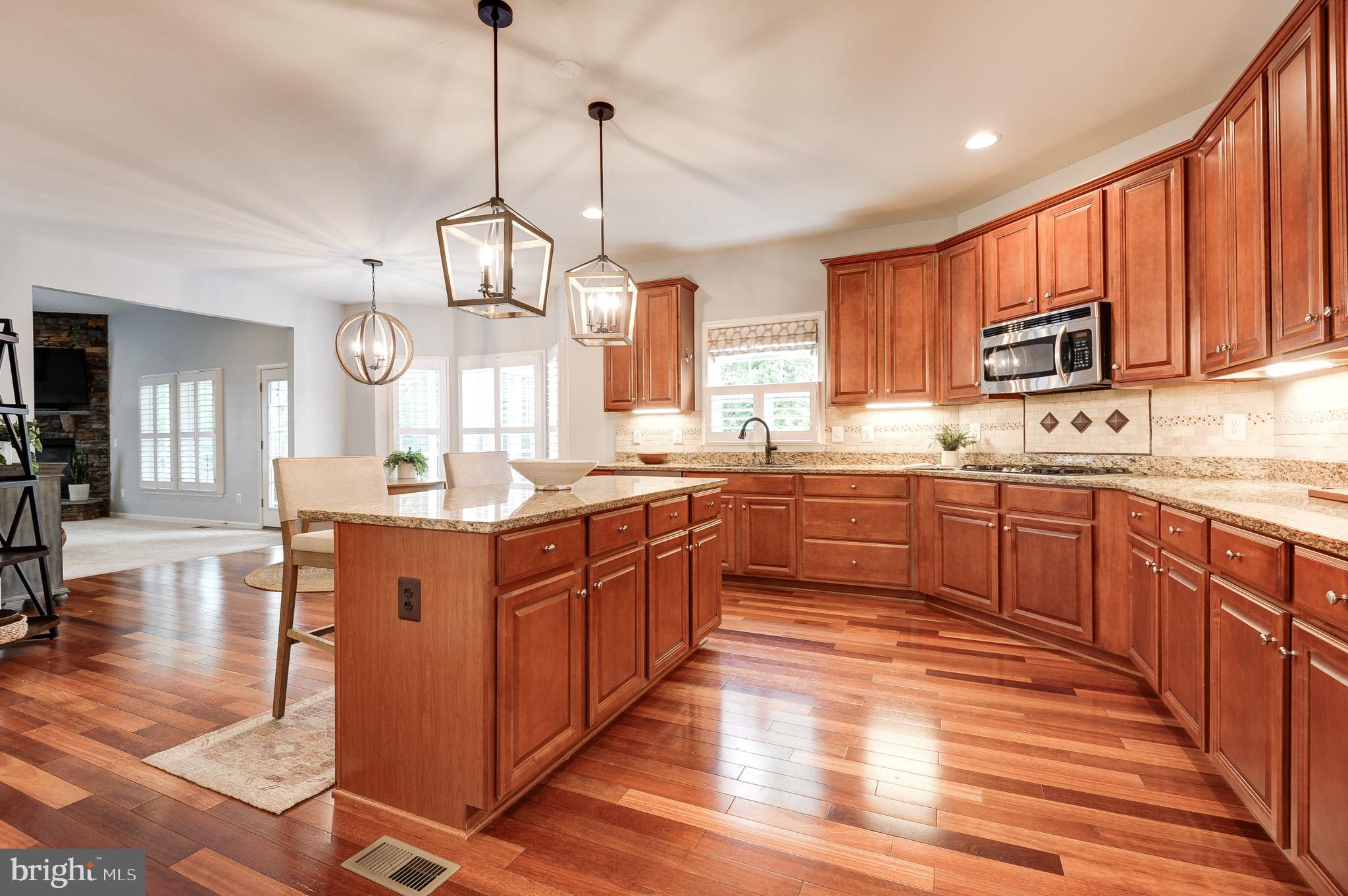 23372 Minerva Drive Brambleton, VA 20148 - Photo 16 of 61 a kitchen with stainless steel appliances granite countertop wooden cabinets a sink dishwasher a dining table and chairs with wooden floor