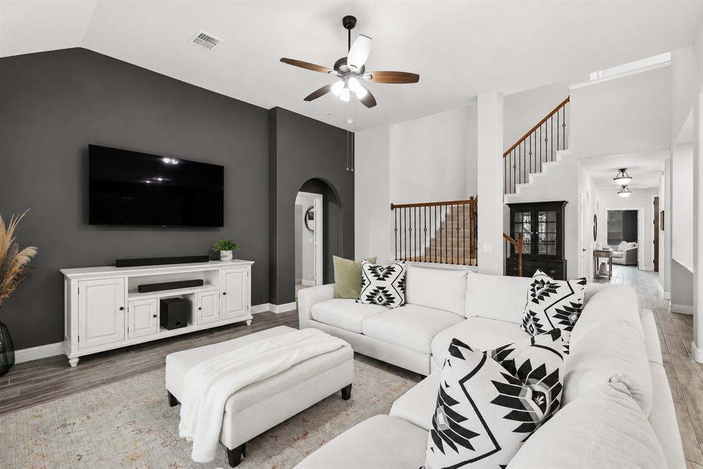 924 Timber Ridge Drive Justin, TX 76247 - Photo 15 of 32 Vaulted ceiling with ceiling fan, wood-finish flooring, two-tone wall finishes, arched doorway, and staircase with wood handrail and metal spindles