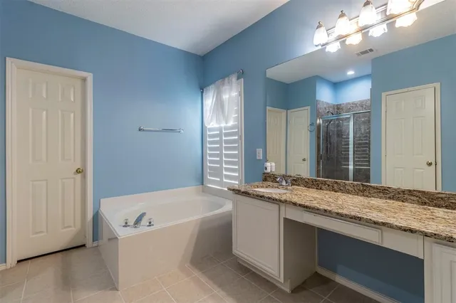 a bathroom with a granite countertop sink a large mirror and a bathtub