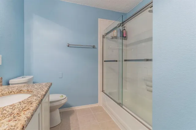 a bathroom with a granite countertop sink a toilet and shower