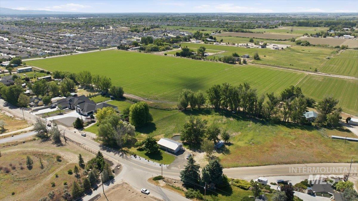 6323 Foothill Road Star, ID 83669 - Photo 40 of 50 Expansive property featuring a large green field, mature trees, a paved road, and distant residential structures