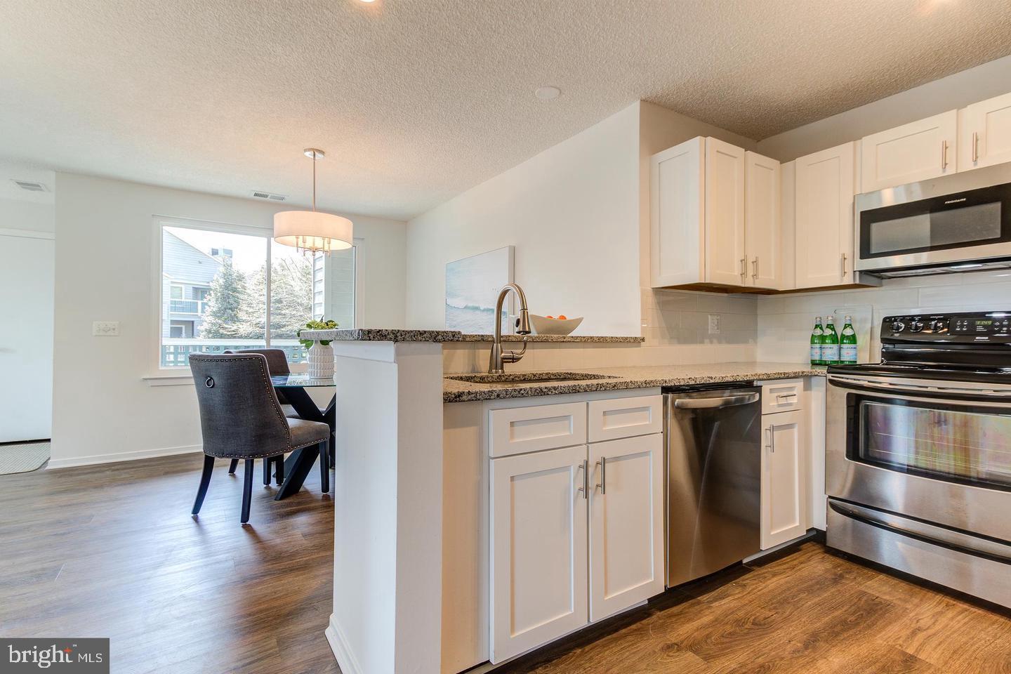 11707 D Summerchase Circle Reston, VA 20194 - Photo 9 of 21 a kitchen with stainless steel appliances granite countertop a kitchen island hardwood floor sink and stove