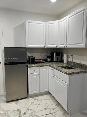 a kitchen with granite countertop a refrigerator sink and cabinets