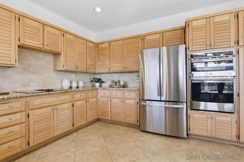 a kitchen with granite countertop stainless steel appliances a refrigerator a sink and cabinets