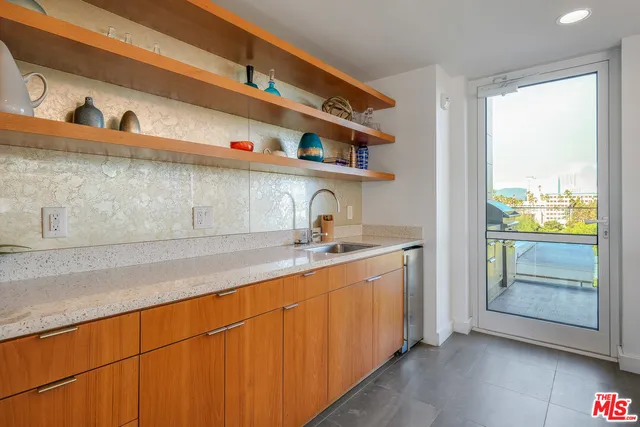 a view of a patio with couches potted plants and wooden floor