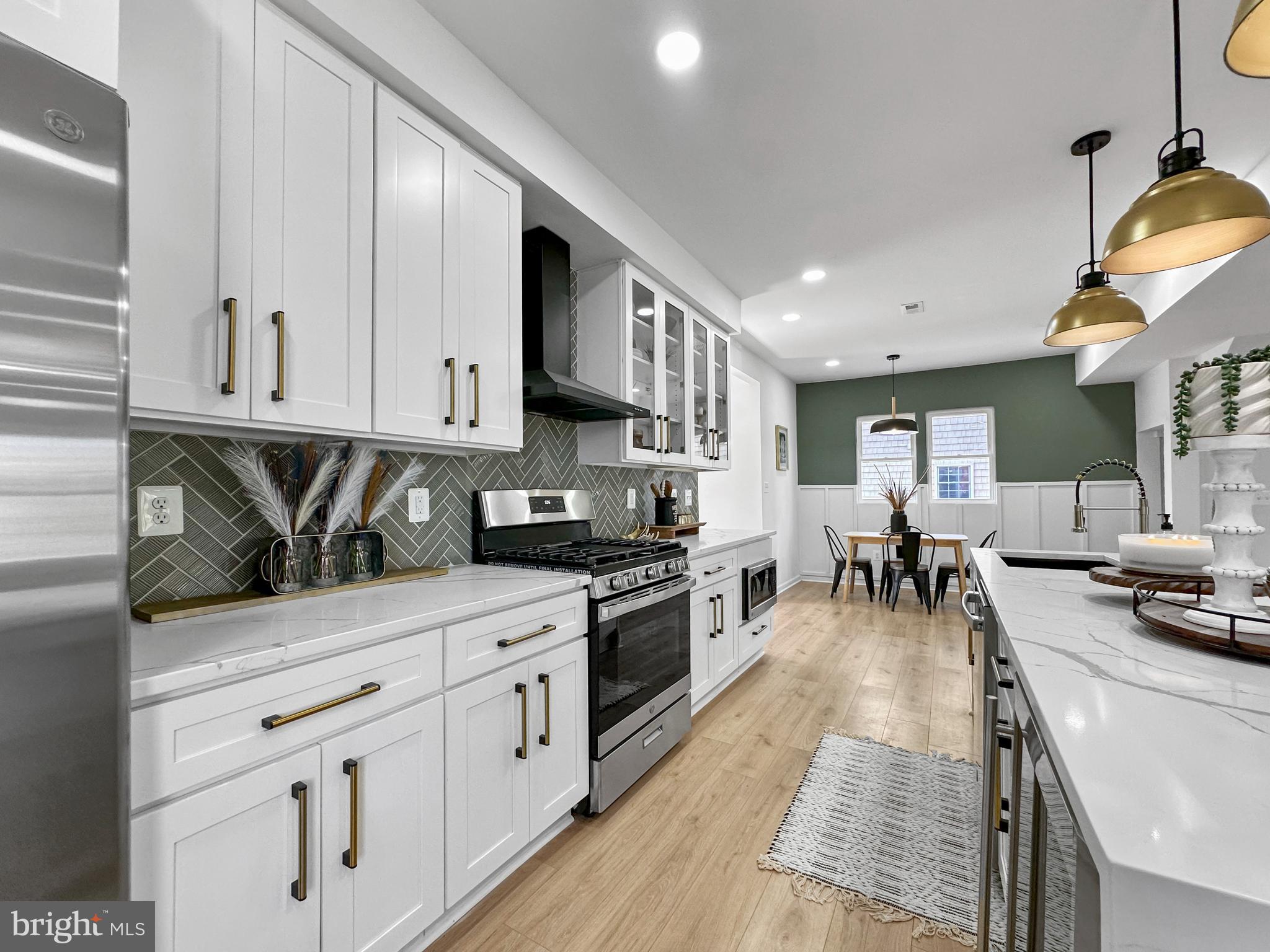 4309 Queensbury Road Riverdale, MD 20737 - Photo 13 of 63 a kitchen with stainless steel appliances granite countertop a stove a sink a refrigerator and white cabinets