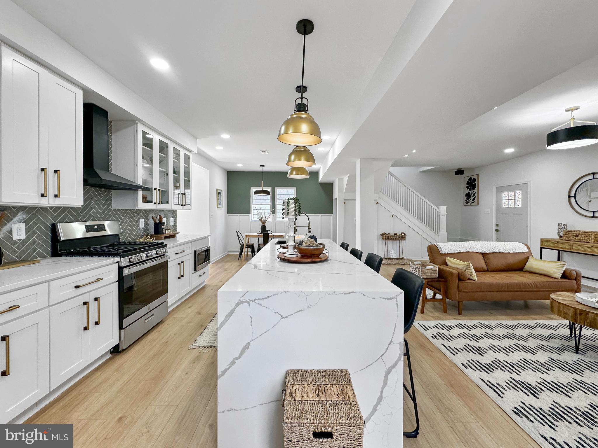 4309 Queensbury Road Riverdale, MD 20737 - Photo 14 of 63 a large kitchen with stainless steel appliances granite countertop a stove a sink dishwasher and white cabinets with wooden floor