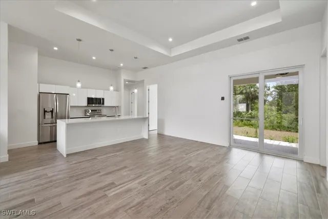 a view of kitchen with granite countertop refrigerator oven and white cabinets with wooden floor