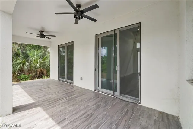 an empty room with wooden floor fan and windows