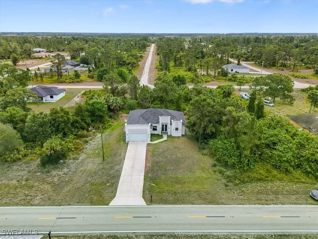 an aerial view of residential houses with outdoor space and trees