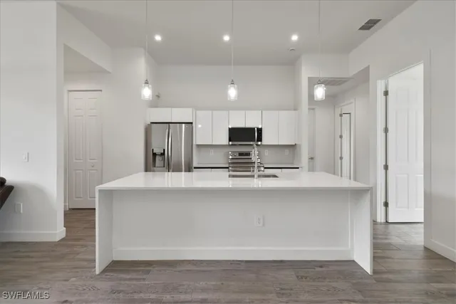 a view of kitchen with stainless steel appliances granite countertop cabinets and wooden floor