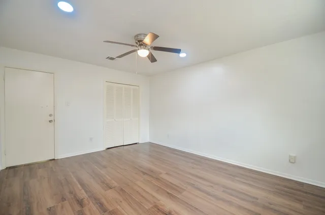 an empty room with wooden floor and windows