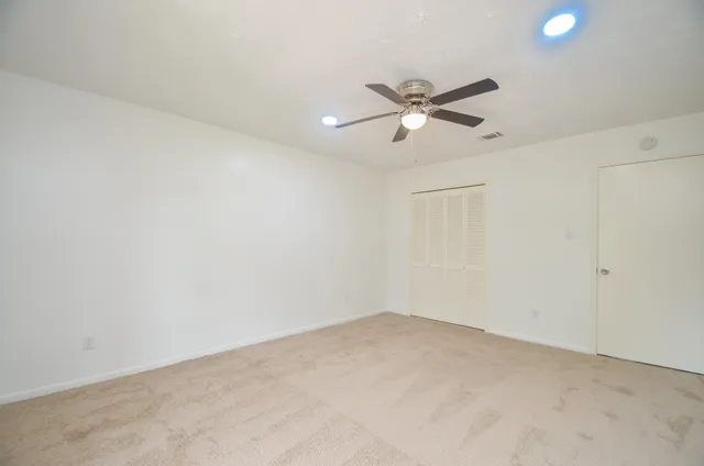 an empty room with windows and fan