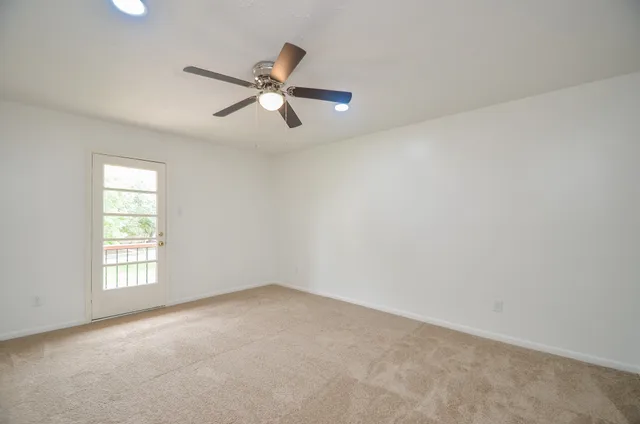 an empty room with windows and fan