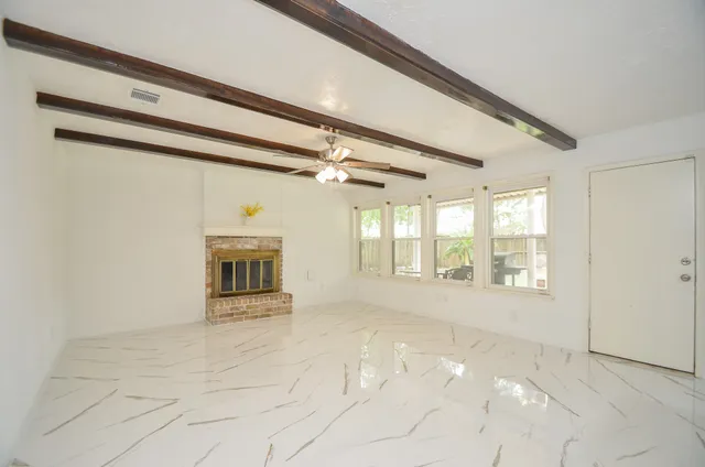 a view of an empty room with a fireplace and a window