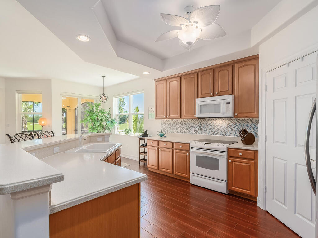 1276 Rialto Way, Unit 102 Naples, FL 34114 - Photo 5 of 37 a kitchen with stainless steel appliances granite countertop hardwood floor sink stove and refrigerator