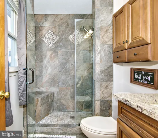 a bathroom with a granite countertop bathtub shower and toilet