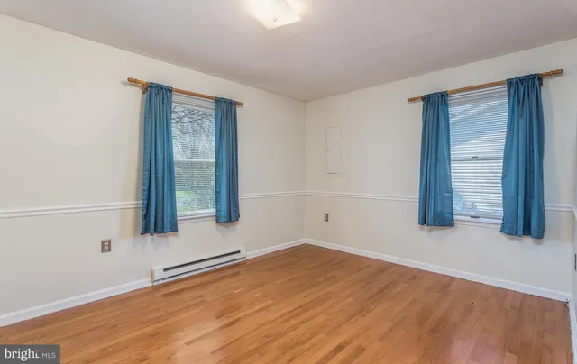 a view of an empty room with wooden floor and cabinet