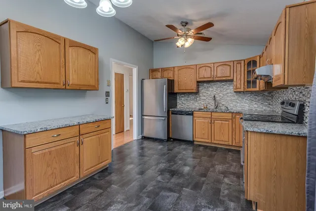 a kitchen with stainless steel appliances granite countertop a sink a stove a refrigerator a washer dryer and white cabinets