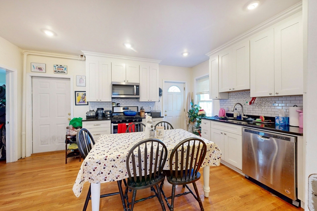 58 Dearborn Street Medford, MA 02155 - Photo 12 of 38 a kitchen with stainless steel appliances granite countertop a dining table chairs refrigerator sink and cabinets