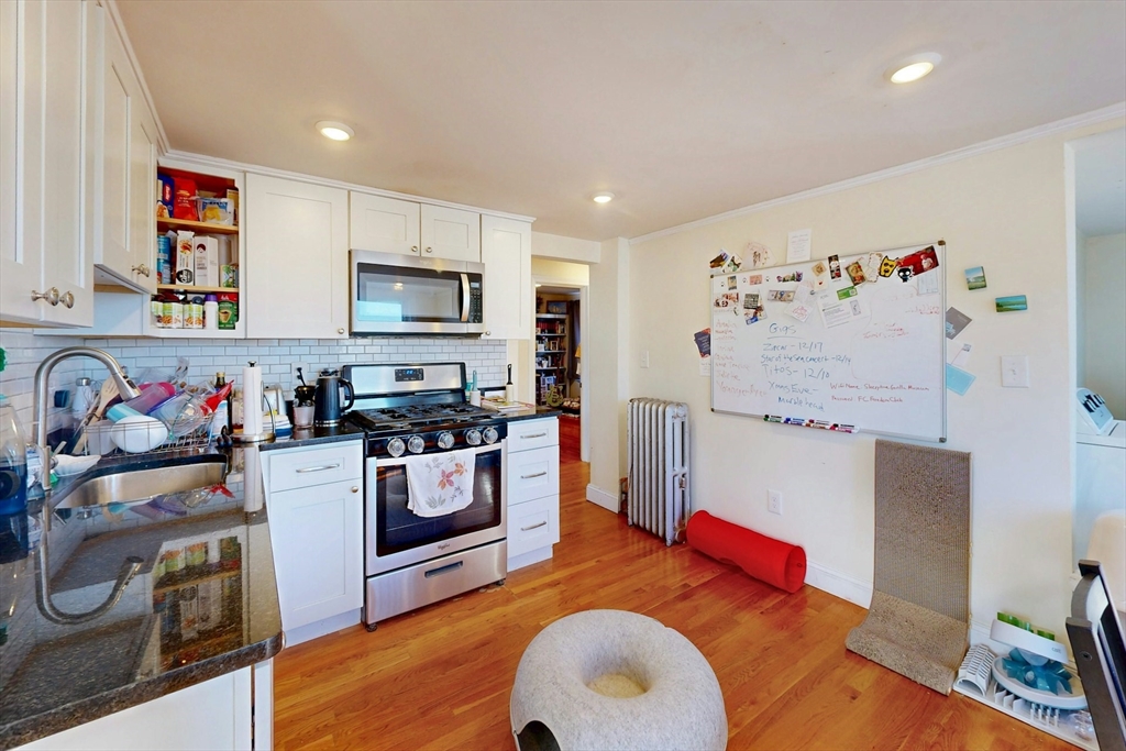 58 Dearborn Street Medford, MA 02155 - Photo 19 of 38 a kitchen with stainless steel appliances granite countertop a stove a sink dishwasher and a refrigerator with wooden floor