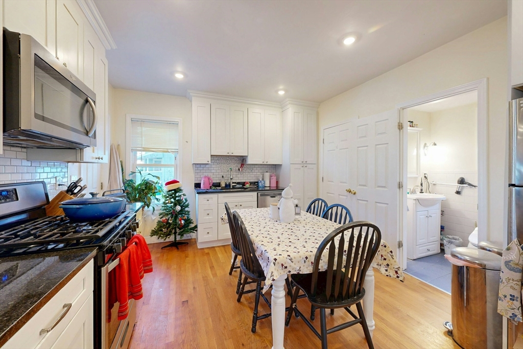58 Dearborn Street Medford, MA 02155 - Photo 9 of 38 a kitchen with stainless steel appliances granite countertop a stove top oven a sink a dining table and chairs with wooden floor