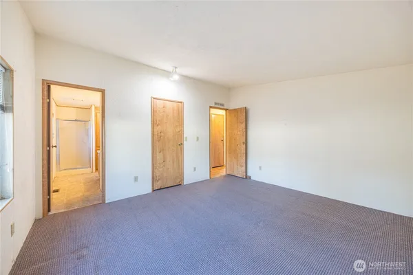 a view of an empty room with closet and a window