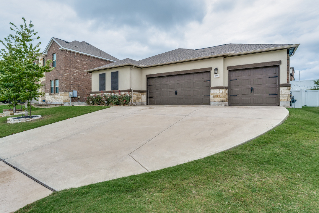 5921 Lehman Way Austin, TX 78747 - Photo 2 of 25 A spacious driveway leads to an inviting home featuring two prominent garage doors.