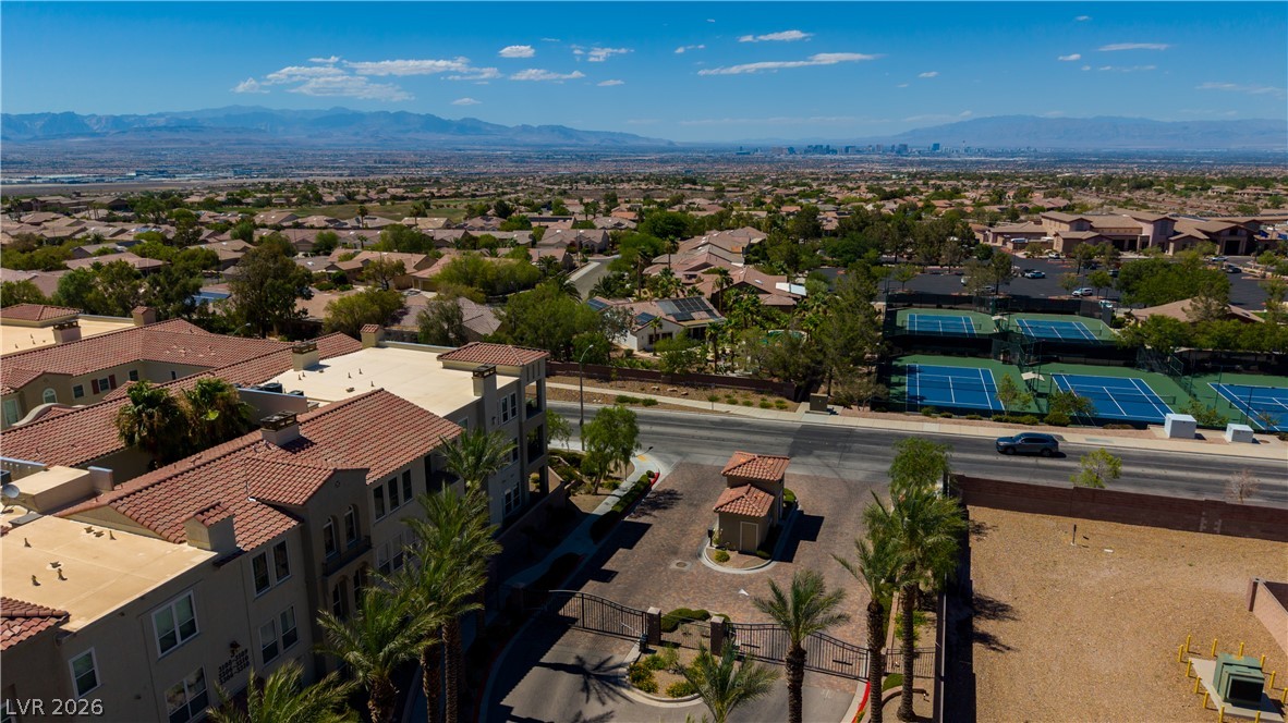 2555 Hampton Road, Unit 3308 Henderson, NV 89052 - Photo 46 of 65 An aerial perspective reveals a gated community, featuring well-maintained tennis courts and distant mountain views.