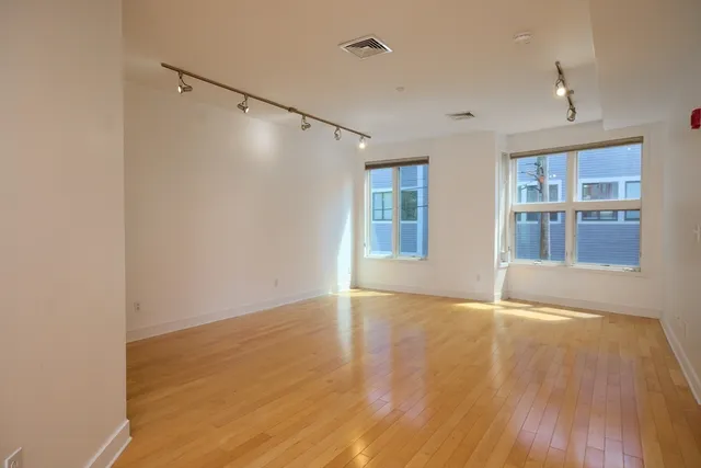 a view of an empty room with window and wooden floor