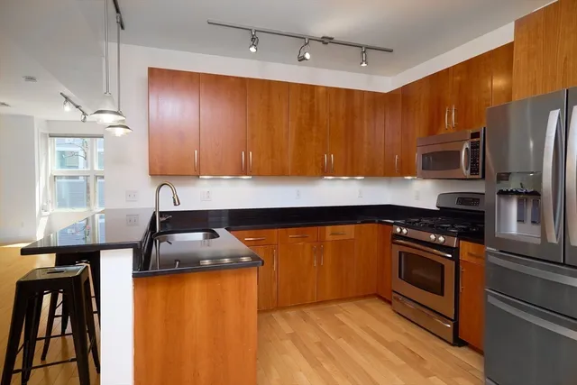 a kitchen with stainless steel appliances granite countertop wooden cabinets a stove top oven a sink and dishwasher