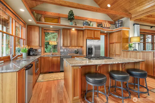a kitchen with stainless steel appliances granite countertop table chairs sink and cabinets