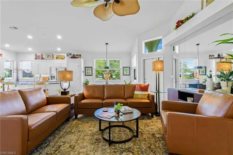 a living room with furniture a rug kitchen view and a chandelier