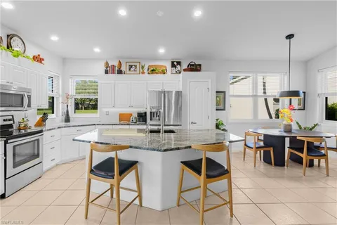 a kitchen with stainless steel appliances granite countertop table chairs sink and cabinets