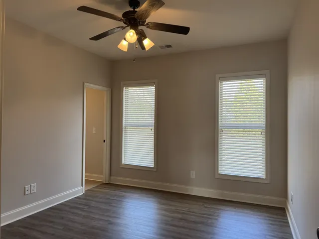 an empty room with wooden floor closet and windows