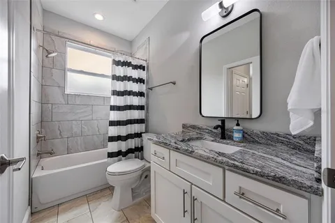 a bathroom with a granite countertop sink toilet mirror and bathtub