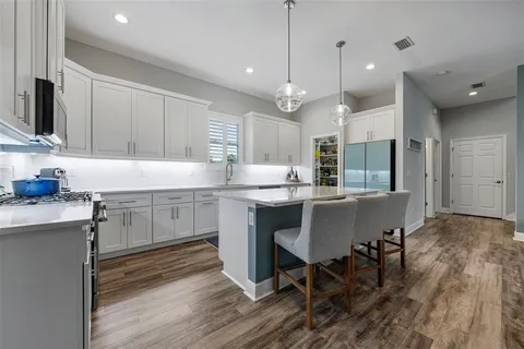 a kitchen with kitchen island granite countertop a sink cabinets and wooden floor