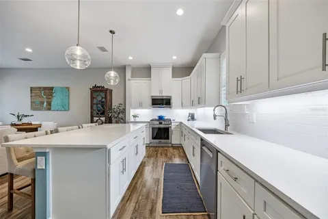 a large kitchen with stainless steel appliances granite countertop a sink a stove and a wooden floors