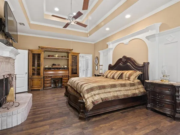a spacious bedroom with a bed a mirror on dresser and a flat screen tv