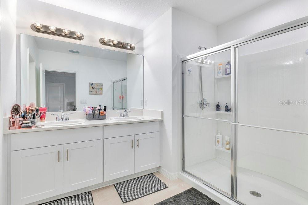 4255 Southern Vista Loop St. Cloud, FL 34772 - Photo 14 of 34 a bathroom with a double vanity sink mirror and shower