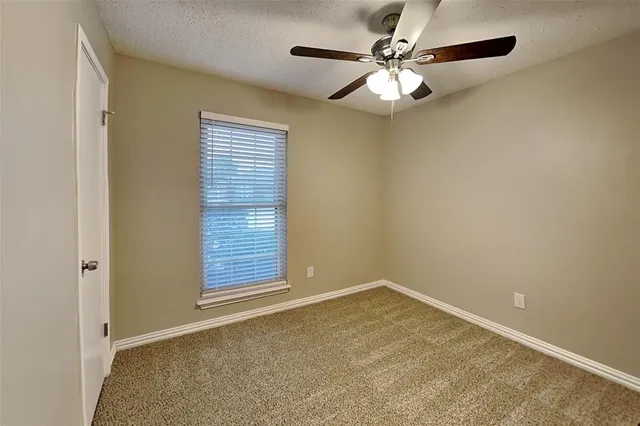 an empty room with a chandelier fan and windows