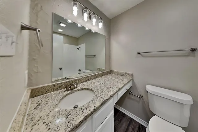 a bathroom with a granite countertop sink a mirror and a toilet