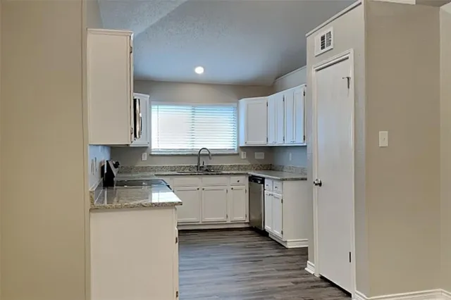 a kitchen with granite countertop white cabinets and white appliances