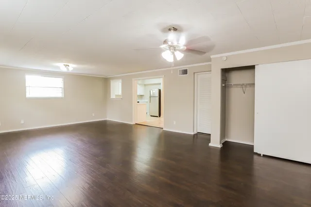 a view of an empty room with wooden floor and a window