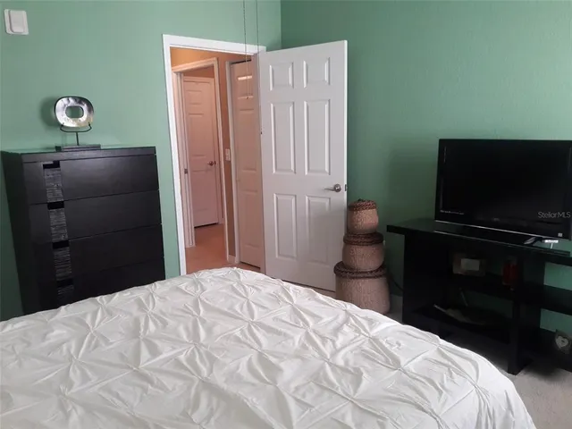 a bedroom with a bed and a flat tv screen on a dresser