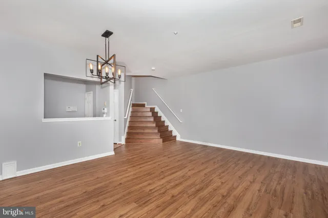 a view of a room with wooden floor staircase and a chandelier